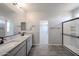 Bright bathroom with double vanity, granite counters, wood tile floor and glass enclosed shower at 18236 W Daley Ln, Surprise, AZ 85387