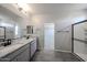 Bright bathroom with double vanity, granite counters, wood tile floor and glass enclosed shower at 18236 W Daley Ln, Surprise, AZ 85387
