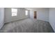 Spacious bedroom featuring soft carpeting, two bright windows, and neutral paint at 18236 W Daley Ln, Surprise, AZ 85387