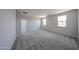 Bright, carpeted bedroom featuring an entry door and large, light-filled windows at 18236 W Daley Ln, Surprise, AZ 85387