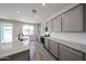 Modern kitchen featuring gray cabinetry, granite counters, stainless steel appliances, and sink island at 18236 W Daley Ln, Surprise, AZ 85387