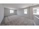 Large loft area with soft carpet, bright windows, and neutral walls offering a versatile living space at 18236 W Daley Ln, Surprise, AZ 85387