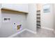 Bright, neutral laundry room featuring white cabinets and a shelving unit with a window at the end at 21093 N Willow Rd, Maricopa, AZ 85138
