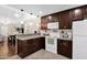 Functional kitchen featuring granite countertops, white appliances, and dark wood cabinets with a seamless flow to the dining area at 2219 E Catalina Dr, Phoenix, AZ 85016