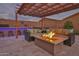 Inviting backyard with a covered patio, fire pit, comfortable seating, and an outdoor bar at 22977 E Desert Spoon Dr, Queen Creek, AZ 85142