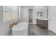 Bright bathroom with a standalone tub, window with blinds, and wood-look tile flooring at 22977 E Desert Spoon Dr, Queen Creek, AZ 85142