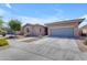 Inviting single-story home with a spacious driveway and manicured front yard landscaping on a sunny day at 22977 E Desert Spoon Dr, Queen Creek, AZ 85142