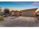 Charming single-story home with a well-maintained lawn and two-car garage at sunset at 22977 E Desert Spoon Dr, Queen Creek, AZ 85142