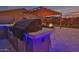 Backyard kitchen island with grill, bar seating and decorative blue lights, under shaded pergola at 22977 E Desert Spoon Dr, Queen Creek, AZ 85142