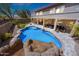 Backyard features a sparkling pool with a rock slide, manicured lawn, and covered patio at 2425 W Woburn Ln, Phoenix, AZ 85085