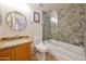 Bathroom with stone-lined shower, wood vanity, updated fixtures, and a decorative vanity mirror at 2425 W Woburn Ln, Phoenix, AZ 85085