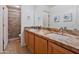 Updated bathroom with dual sinks, granite countertops, tile flooring, framed mirror, and a tiled walk-in shower at 2425 W Woburn Ln, Phoenix, AZ 85085