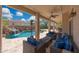 Inviting covered patio features stylish seating, ceiling fans, and views of the pool and waterfall at 2425 W Woburn Ln, Phoenix, AZ 85085