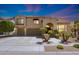 Inviting two-story home with lush landscaping, an arched entryway, and a spacious three-car garage at dusk at 2425 W Woburn Ln, Phoenix, AZ 85085