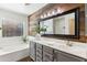 Modern bathroom featuring a wood accent wall, bathtub, and sink with neutral cabinets and a large framed mirror at 2768 W Jasper Butte Dr, San Tan Valley, AZ 85144