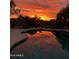 Backyard pool reflecting a colorful sunset in a fenced yard with mature trees and desert landscaping at 346 W Oxford Ln, Gilbert, AZ 85233