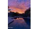 Backyard pool reflecting a beautiful sunset in a fenced yard with mature trees and desert landscaping at 346 W Oxford Ln, Gilbert, AZ 85233