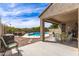 Relaxing covered backyard patio with patterned rug, seating, and view of the pool, and green landscaping at 3810 S Star Canyon Dr, Gilbert, AZ 85297