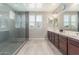 Bathroom with dual sinks, dark wood cabinets, large mirror, and walk-in shower at 3850 E Robert St, Gilbert, AZ 85295