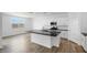 Modern kitchen featuring white cabinets, stainless steel appliances, a black countertop island, and wood-style flooring at 4064 E Ghost Flower Ln, San Tan Valley, AZ 85140