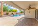 Covered back patio featuring brick tile, ceiling fan, and serene view of a private pool and landscaped yard at 4214 E Morrow Dr, Phoenix, AZ 85050