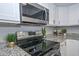 Close-up of stove in a modern kitchen with granite countertops and white cabinets at 4730 W Northern Ave # 1141, Glendale, AZ 85301