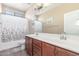This bathroom includes double sinks, cherry wood cabinets, neutral wall paint and a patterned shower curtain at 5635 W Pecan Rd, Laveen, AZ 85339