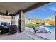 Relax in this covered patio with a ceiling fan, outdoor seating, and views of the pool at 5919 S Banning St, Gilbert, AZ 85298