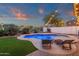 Beautiful backyard pool area with lounge chairs, surrounded by lush greenery and illuminated by string lights at 5919 S Banning St, Gilbert, AZ 85298