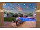 Relaxing pool view from covered patio, showcasing the backyard oasis with lounge chairs and lush greenery at 5919 S Banning St, Gilbert, AZ 85298