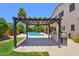 A covered patio and outdoor kitchen overlook the pool in this backyard oasis at 6570 S Pewter Way, Chandler, AZ 85249