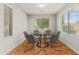 Dining room with modern table, seating for six, wood flooring, and natural light from two windows at 6843 S 46Th Dr, Laveen, AZ 85339