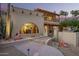 A front exterior view of the home at dusk, featuring a beautiful, unique arched window with brick and desert landscaping at 7131 N 40Th St, Paradise Valley, AZ 85253