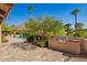Outdoor patio with grill, lush greenery, and a pool in the background, creating a private and inviting space at 7131 N 40Th St, Paradise Valley, AZ 85253