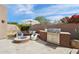 Outdoor kitchen and BBQ area featuring built-in grill, prep space, seating and a fire pit for entertaining at 7169 E Bramble Berry Ln, Scottsdale, AZ 85266