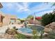 Desert backyard features a stone-lined pool, patio seating, and a built-in grill at 7169 E Bramble Berry Ln, Scottsdale, AZ 85266