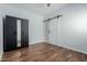 Bedroom featuring a sliding barn door, wood-look flooring, and a black wardrobe cabinet at 7204 S Golfside Ln, Phoenix, AZ 85042