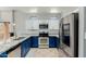 Well-appointed kitchen featuring white and blue cabinetry, granite countertops, stainless steel appliances, and ample natural light at 7204 S Golfside Ln, Phoenix, AZ 85042