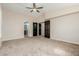 Large main bedroom with neutral carpet, ceiling fan, and a view into the main bathroom and closets at 7204 S Golfside Ln, Phoenix, AZ 85042
