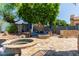 Relaxing backyard with a pool, spa, fire pit, built in seating and mature tree providing ample shade at 7242 W Aurora Dr, Glendale, AZ 85308