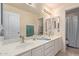 Well-lit bathroom featuring dual sinks, tile flooring, and neutral color scheme at 7242 W Aurora Dr, Glendale, AZ 85308