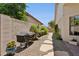 Narrow backyard area with a grill, garden bed, gravel path, and stone pavers at 7508 E Aster Dr, Scottsdale, AZ 85260