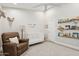 Bedroom featuring vaulted ceilings, brown recliner, white crib, and decoratively-shelved books at 7508 E Aster Dr, Scottsdale, AZ 85260
