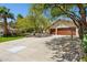 Wide driveway approaching a charming single-story home with a lushly landscaped yard and mature shade trees at 7508 E Aster Dr, Scottsdale, AZ 85260