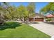 Charming single-story home featuring lush landscaping, green grass, mature trees and a two-car garage at 7508 E Aster Dr, Scottsdale, AZ 85260