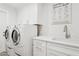 Laundry room showcases side-by-side washer and dryer with white cabinets and sink at 7508 E Aster Dr, Scottsdale, AZ 85260
