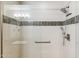 Modern walk-in shower with glass door and white tile with a decorative band at 7601 E Indian Bend Rd # 3002, Scottsdale, AZ 85250