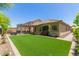 Backyard with artificial turf, covered patio, desert landscaping, and pavers at 14208 W Larkspur Dr, Surprise, AZ 85379