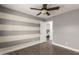 Bedroom features a ceiling fan, gray tone walls, and gray and beige horizontal stripes on an accent wall at 14208 W Larkspur Dr, Surprise, AZ 85379