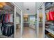 Hallway between two walk-in closets leads to a spa-like bathroom with dual sinks and a soaking tub with views at 15020 S 25Th St, Phoenix, AZ 85048